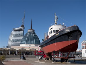 Tugboat Stier in the German Maritime Museum and in the background the glass dome of the restaurant and modern futuristic skyscrapers ATLANTIC Hotels SAIL City
