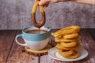 Woman dipping a churro in hot chocolate in a blue and white mug