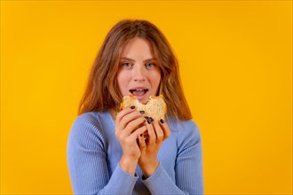 Vegetarian woman biting a sandwich on a yellow background