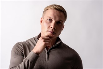 Portrait of a blond german model with a brown sweater on a white background