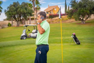 Businessman playing golf and answering a work call with the phone from the club