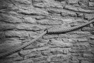 Hemp rope as railing in front of old natural stone wall