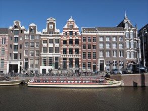 Historic merchant houses on the Herengracht in the old town and tourist boat