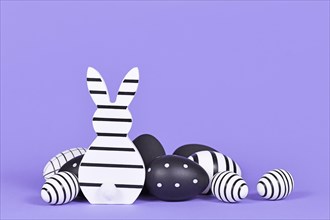 Modern black and white easter bunny ornament and eggs on violet background