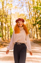 Red-haired woman in a beret walking through a city forest park at sunset