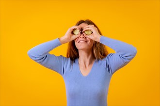 Vegan woman with cucumber slices on her eyes on a yellow background