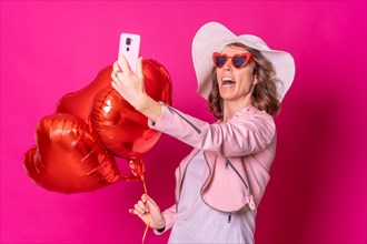 Portrait of a caucasian woman having fun with a white hat in a nightclub with some heart balloons