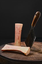 Large beef bone marrow chopped with cleaver on half on wooden stump