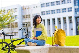Portrait of smiling asian female student sitting in college campus on break