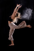 Young dancer performing a jump on a black background