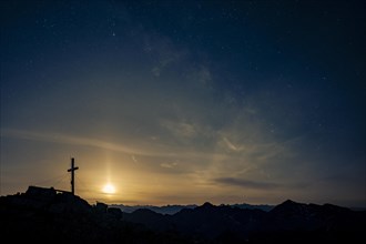 Summit cross of the Namloser Wetterspitze at full moon and Lechtaler Alps