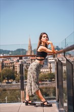 Posing of a young woman on the terrace of a hotel looking at the city from above