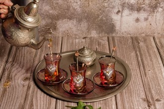 Serving hot Moorish tea on a tray with glasses and pitcher on a wooden table