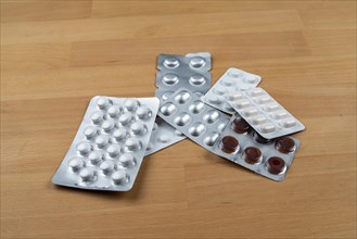Blister packs of various medicines lie on a wooden table
