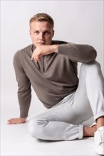 Blond caucasian model with brown sweater on a white background