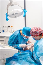 Female dentists in blue scrubs performing a complicated operation on a female patient