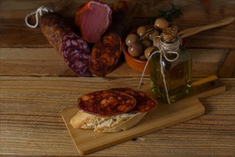 Tapa of iberian chorizo on rustic bread with olive oil on a wooden board with black background