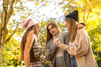 Women friends talking in a park in autumn at sunset