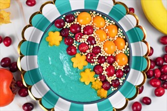 Top view of healthy yogurt and fruit smoothie bowl with natural green spirulina powder decorated with cranberries
