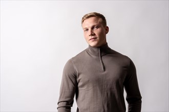Portrait of an attractive blond german model in a brown sweater on a white background