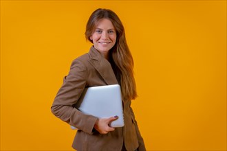 Portrait of a businesswoman with a computer on a yellow background