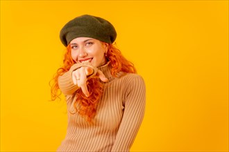 Red-haired woman in a beret in studio on a yellow background