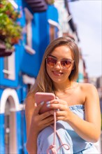 Portrait of young attractive blonde woman in sunglasses looking at the phone