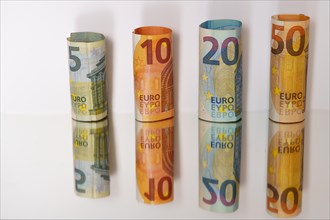 Rolled euro banknotes reflected in a mirror with copy space