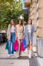 Girlfriends shopping in the offers of the city stores with paper bags