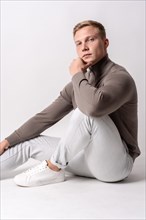 Caucasian blond model with a brown sweater on a white background