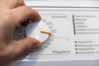 Hand on the temperature control of a washing machine