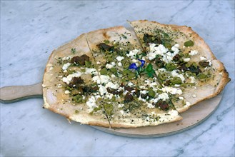 Flammkuchen with olives dried tomatoes and feta cheese on a wooden board