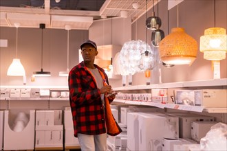 Black ethnic man shopping in a supermarket for lamps