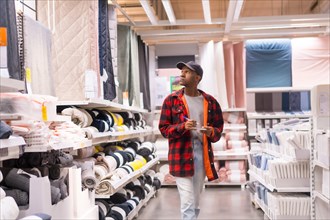 Black ethnic man shopping in a supermarket for bath mats and towels