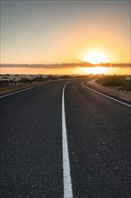 Empty asphalt road through the desert or dunes. Sunrise over the road