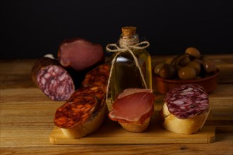Assorted iberian sausage tapas on a wooden board with a black background