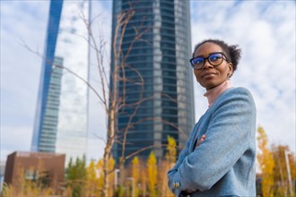 Portrait of black ethnic businesswoman or executive wearing glasses standing in business park