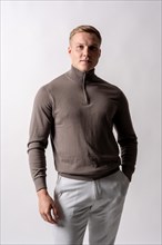 Portrait of an attractive blond german model with a brown sweater on a white background