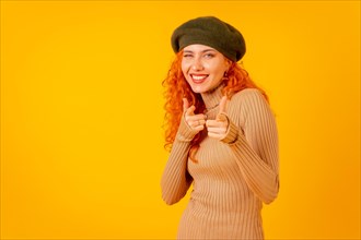 Red-haired woman in beret in studio on a yellow background