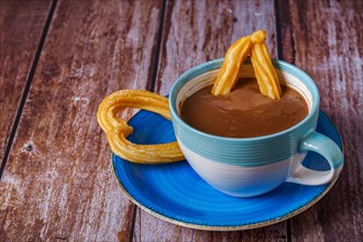 Hot chocolate with a churro in the form of a heart on a wooden table