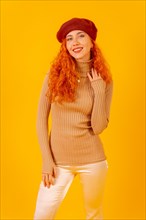 Portrait of red-haired woman in a red beret on a yellow background
