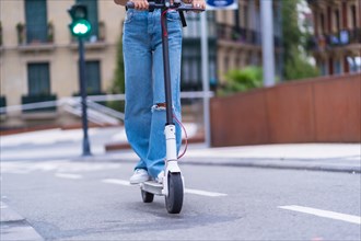 Detail of a young brunette woman moving in the city with an electric scooter