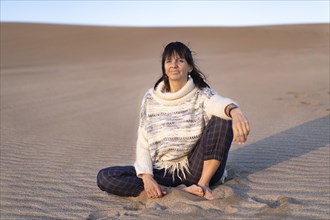 A woman looking at camera at sunset in a dune. Copy space
