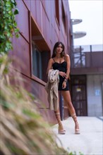 Posing of a young woman in the city with a black skirt on a brown building