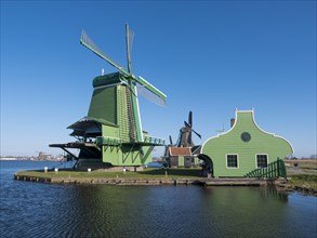 The green windmill De Gekroonde Poelenburg on the banks of the river Zaan in the museum village Zaanse Schans
