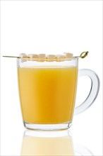Hot non alcohol drink with orange juice and coconut milk served with pieces of coconut on skewer