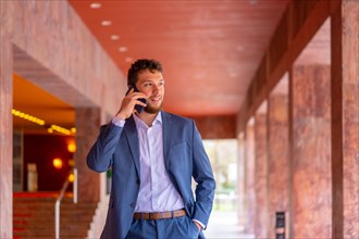 Business or finance corporate man at the entrance of an event in a hotel with the phone