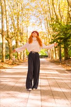 Red-haired woman walking through a city forest park smiling at sunset