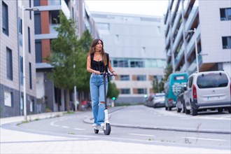 A young brunette woman moving in the city with an electric scooter