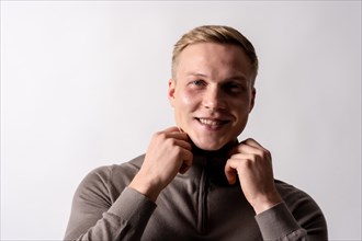 Portrait of an attractive blond german model with brown sweater on a white background